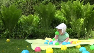 erkek bebek fern bitkiler yakınındaki ekose renkli topları arasında iyi eğlenceler. 4k