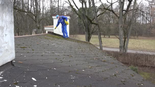 Homem com spray respirador musgo com produtos químicos crescendo no telhado da casa — Vídeo de Stock