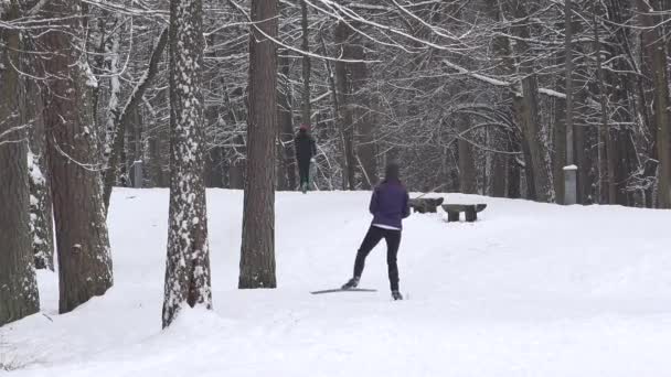 Mujer esquiadora esquiando en pista de esquí y hombre corredor en el parque de invierno. 4K — Vídeos de Stock