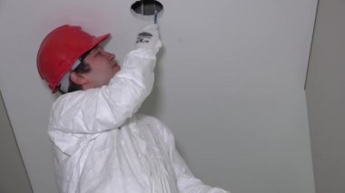 Yorgun erkek işçi kırmızı kask kesme tavan delikler ile