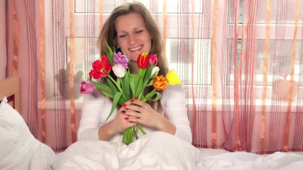 Mujer bonita chica con tulipanes de colores y mirando a la cámara y la flor que huele — Vídeo de stock