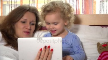Tablet bilgisayar ile eğleniyor yatakta anne bebek bakıcısı ile mutlu çocuk.