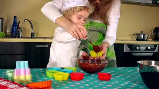 Madre e piccola figlia carina stanno sorridendo mentre riempiono i casi di muffin colorati — Video Stock