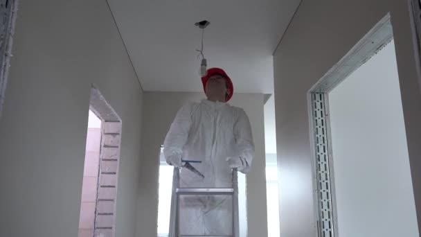 Electrician man with helmet climb up on ladder and unscrew light bulb — Stock Footage Electrician man with helmet climb up on ladder and unscrew light bulb Royalty Free Stock Video