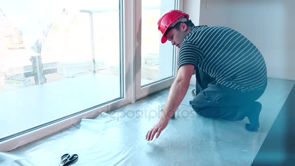 Bouwvakker leggen polyethyleenfilm op verdieping. — Stockvideo