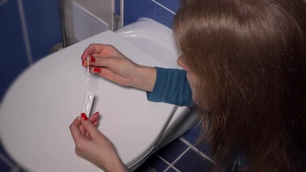 Жінка робить тест на вагітність з піпеткою на кришці шафи і чекає результату — стокове відео