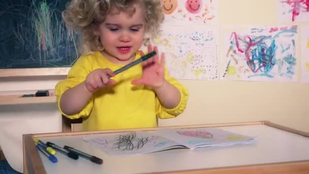 Забавна дитяча картина художника з олівцем на папері, що сидить біля столу — стокове відео
