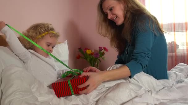 Alegre madre e hija unboxing regalo caja en el dormitorio — Vídeo de stock