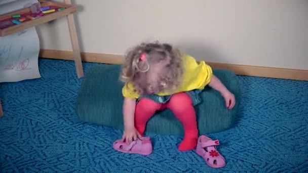 Nervózní dívka si hraje s její boty. Dítě nemůže dát sandál na — Stock video