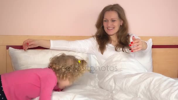 Uma menina marota veio para a cama e abraçou a mãe. Adoráveis meninas da família se divertir — Vídeo de Stock