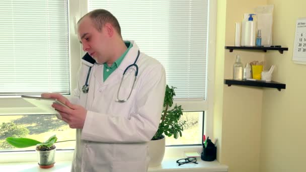 Doctor holding tablet computer while calling patient in hospital cabinet — Stock Video