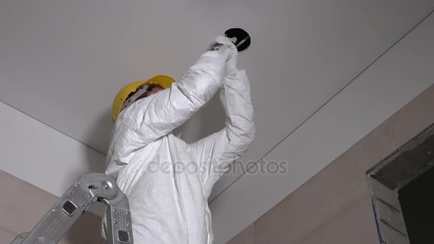 Skilled constructor man making plasterboard ceiling holes for light installation — Stock Video