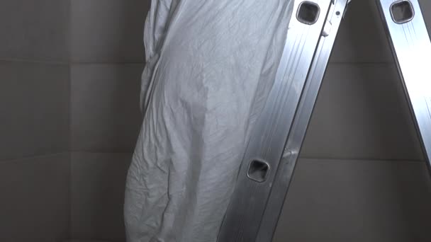 Worker Man On Ladder Cutting Hole In Drywall Ceiling For Lighting