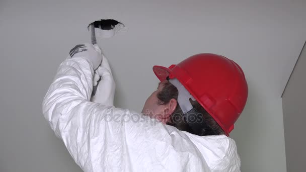 Trabajador masculino con agujeros cortados a mano en el techo de paneles de yeso para la instalación de iluminación — Vídeos de Stock