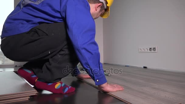 Travailleur charpentier installant un plancher stratifié dans la pièce — Video