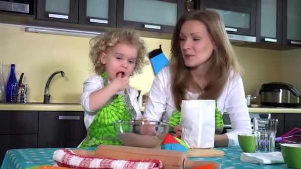 Kleine Mütterhelferin schmeckt Schokoladenkuchenmehl und mischt es mit einem Löffel — Stockvideo