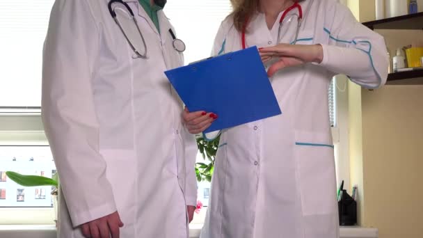 Médico varón consultando colega femenino con carpeta en las manos — Vídeo de stock