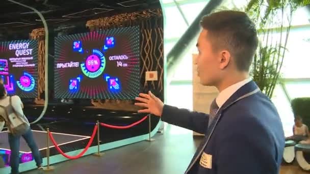 Männliche Exposition Führer zeigt Mann auf interaktive Energie Quest Brettspiel — Stockvideo