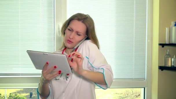 Mujer doctora sosteniendo tableta mientras llama al paciente en el gabinete del hospital — Vídeos de Stock