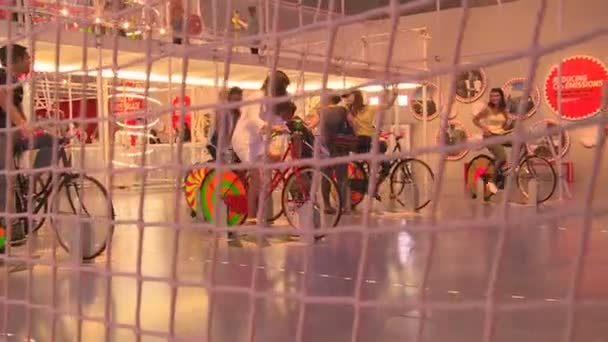 Visiteurs de l'exposition personnes assises sur des vélos à pédales générant de l'électricité — Video