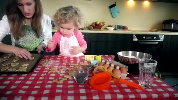 Preciosa madre e hija colocan galletas galletas a la placa del horno de estaño en la cocina — Vídeo de stock