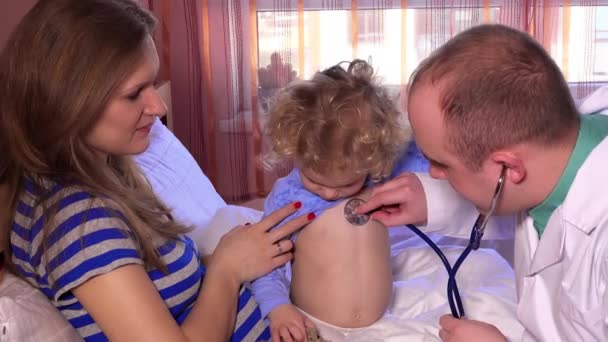 Mother and smiling cute daughter at pediatrician. Doctor using stethoscope — Stock Video