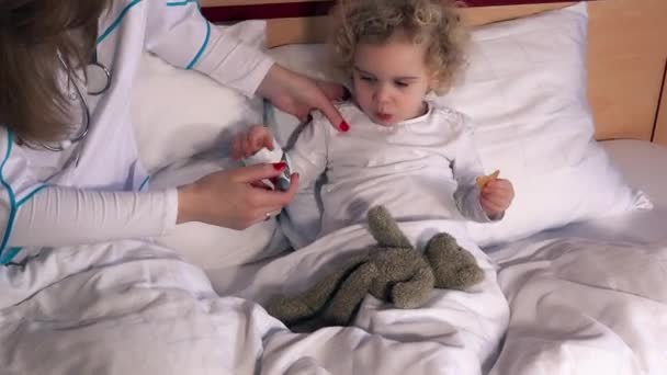 Врач, измеряющий температуру маленькой девочки в смотровой — стоковое видео