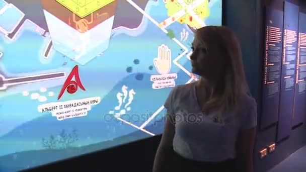 Mujer guía tocando pared colorida interactiva en el pabellón de Mónaco — Vídeo de stock
