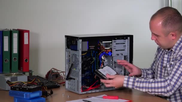 Young repairer man installing hard drive into desktop pc case at computer center — Stock Video