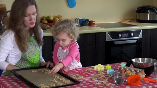 Preciosa madre e hija colocan galletas galletas a la placa del horno de estaño en la cocina — Vídeo de stock