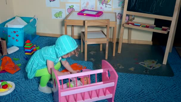 Dulce niña pequeña acostada muñeca en la cama de juguete cubierta con manta — Vídeos de Stock