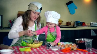 Anne ve sevimli çocuk kurabiye hamuru mutfak içine haşhaş tohumu koymak