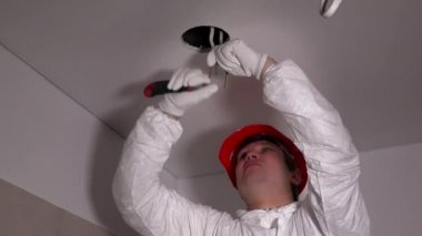Koruyucu iş giysisi içinde yakışıklı elektrikçi kablo yalıtımı bıçakla kaldırmak