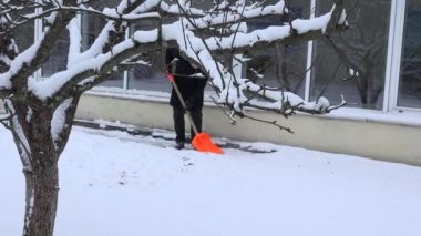 adam temiz karlı yol ev duvar kış boyunca kürek ile. 4k