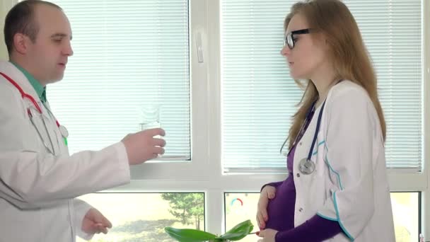 Collega medic arts geven een pil en een glas water voor zwangere vrouw — Stockvideo