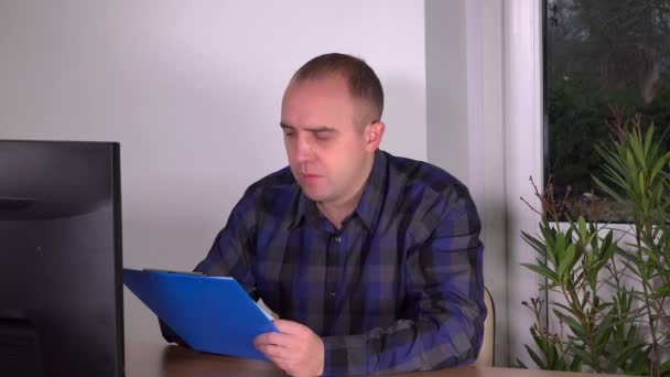 Деловой человек проверяет документы буфера обмена, просматривает экран компьютера в офисе — стоковое видео