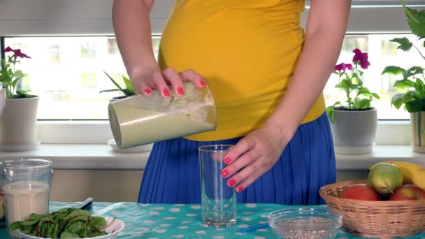 Pregnant female hands pour healthy fruit cocktail into glass — Stock Video