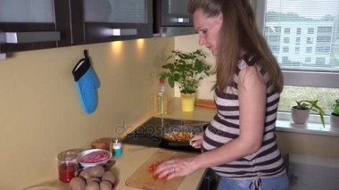 Gelecekte anne büyük mide ile domates ve pan pişirme içine koydu