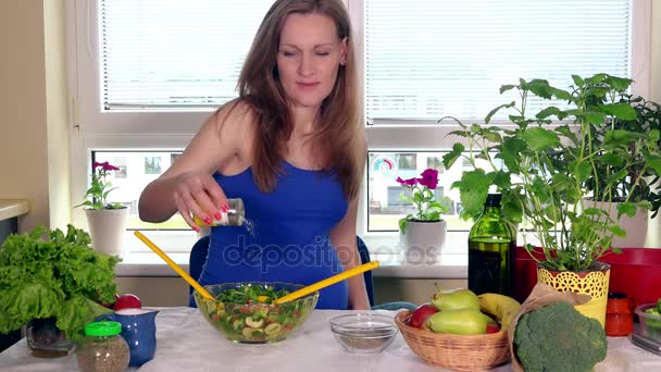 Улыбающаяся будущая мать наливает соль и смешивает экологический салат из натуральных овощей — стоковое видео