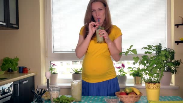 Щаслива майбутня мама п'є фруктовий коктейль і пестить її великий живіт — стокове відео