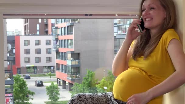 Щаслива емоційна вагітна жінка говорить на своєму смартфоні — стокове відео