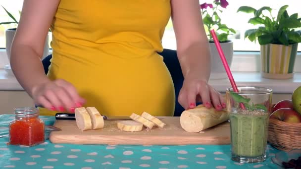 Mulher grávida barriga e mãos cortando baguete e preparar pão com caviar — Vídeo de Stock