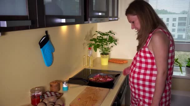미래의 임신 어머니 요리 부엌 홉에 팬에 고기와 야채를 혼합 — 비디오