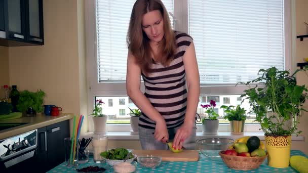 Pregnant young woman preparing cutting pear fruit in kitchen at home — Stock Video