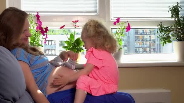 Usmívající se těhotná žena s dcerou doma. Šťastná rodina — Stock video