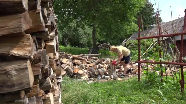 Holzstapel und Bauer bereiten im Hinterhof Brennholz zu. 4k — Stockvideo