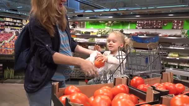 Kobieta w ciąży z cute dziecko zbierając owoce pomidorów w supermarkecie — Wideo stockowe