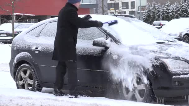 Hombre limpio coche ventana nevada con cepillo en invierno. 4K — Vídeos de Stock