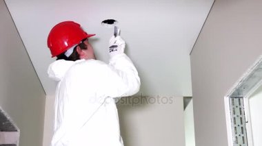 Genç erkek elektrikçi tavan el testeresi ile kesme delik