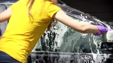 Kadın işçi çamaşır araba oto yıkama üzerine sünger ile